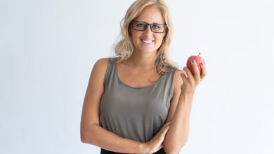 Femme avec des lunettes tenant une pomme dans la main