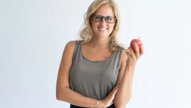 Femme avec des lunettes tenant une pomme dans la main
