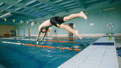 Homme en mallot de bain noir qui plonge dans une picine